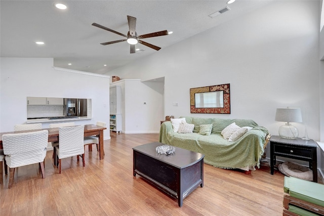 living room featuring vaulted ceiling, ceiling fan, and light wood-type flooring