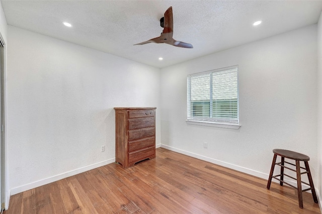 unfurnished room featuring hardwood / wood-style flooring, ceiling fan, and a textured ceiling