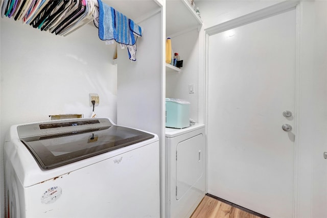 laundry room with washer and clothes dryer and light wood-type flooring