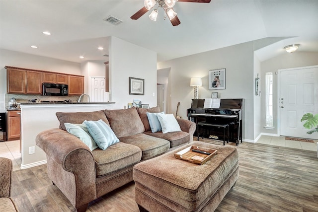 living room featuring wood-type flooring, ceiling fan, and vaulted ceiling