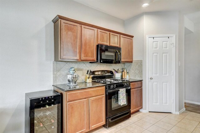 kitchen with black appliances, backsplash, light wood-type flooring, dark stone countertops, and wine cooler