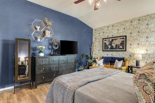 bedroom with ceiling fan, lofted ceiling, and light hardwood / wood-style floors