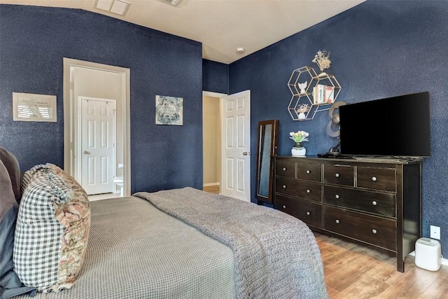 bedroom with light hardwood / wood-style floors and ensuite bath