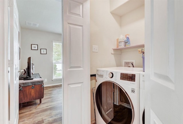 laundry room with washer / dryer and light hardwood / wood-style floors