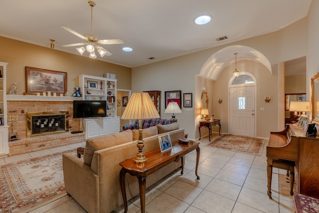 tiled living room featuring a fireplace and ceiling fan