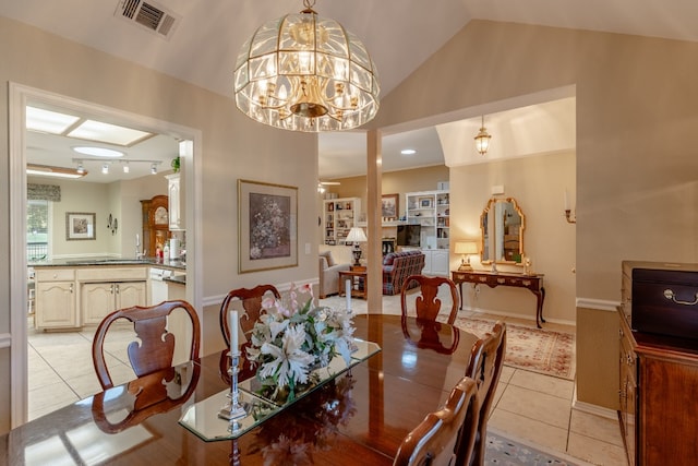 dining space featuring vaulted ceiling, an inviting chandelier, light tile patterned floors, rail lighting, and built in shelves