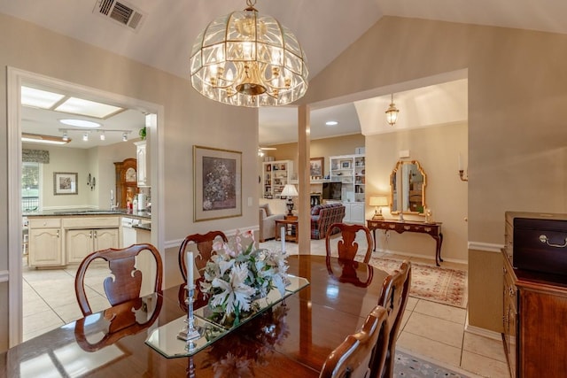 dining space with an inviting chandelier, lofted ceiling, and light tile patterned floors