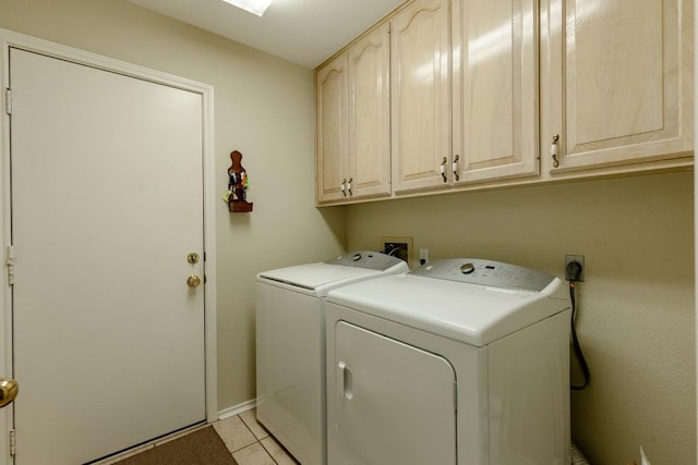 clothes washing area featuring cabinets, light tile patterned flooring, and washing machine and clothes dryer