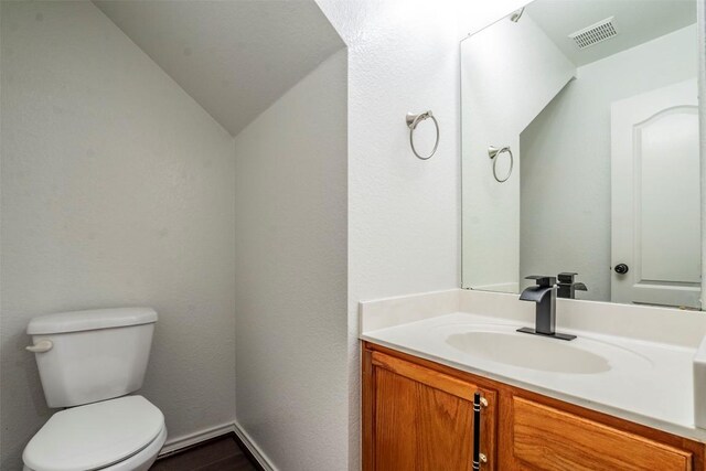 bathroom featuring vanity, toilet, and lofted ceiling