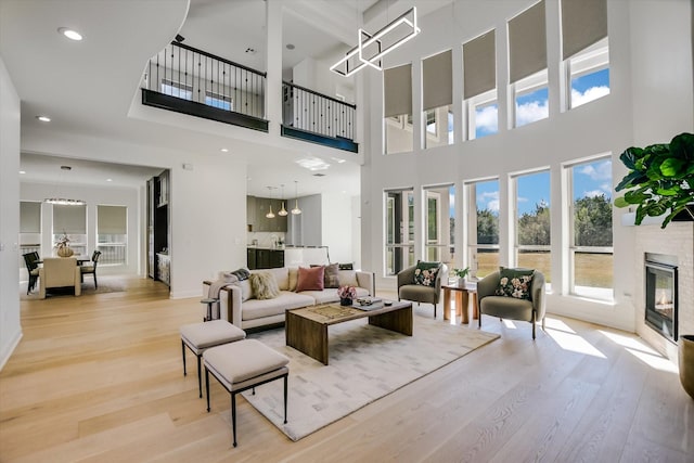 living room featuring an inviting chandelier, a towering ceiling, and light hardwood / wood-style flooring