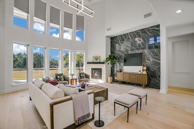 living room with a fireplace, light hardwood / wood-style flooring, and a high ceiling