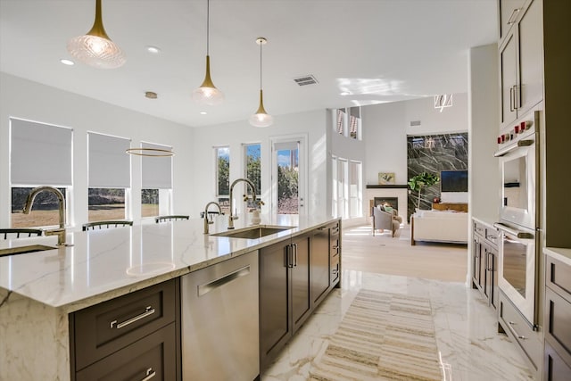 kitchen featuring stainless steel appliances, light stone countertops, sink, and pendant lighting