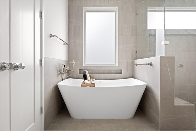 bathroom featuring a tub to relax in, tile patterned flooring, and tile walls