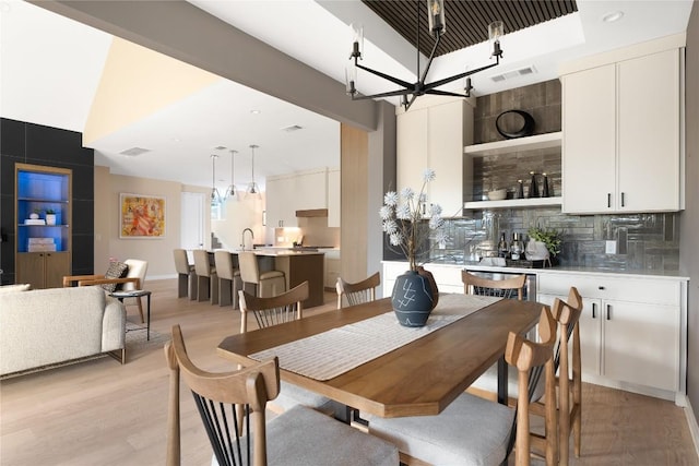 dining area with sink, an inviting chandelier, and light hardwood / wood-style floors