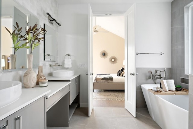 bathroom featuring tile walls, backsplash, vanity, tile patterned floors, and a tub