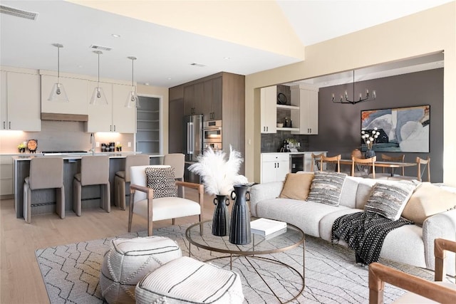 living room featuring wine cooler, an inviting chandelier, and light hardwood / wood-style flooring