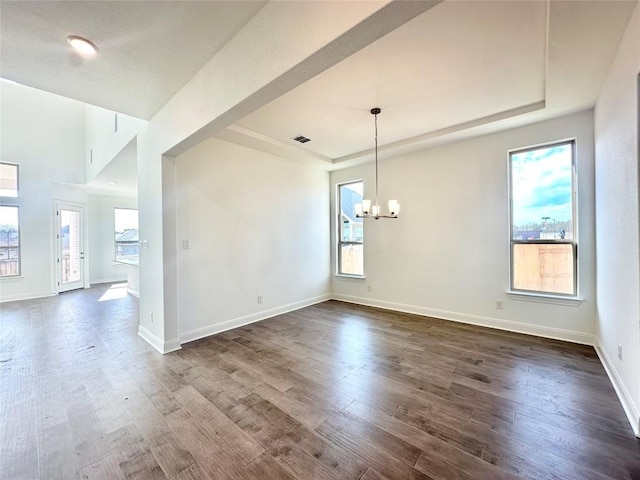 empty room with dark wood-style floors, a healthy amount of sunlight, baseboards, and a tray ceiling