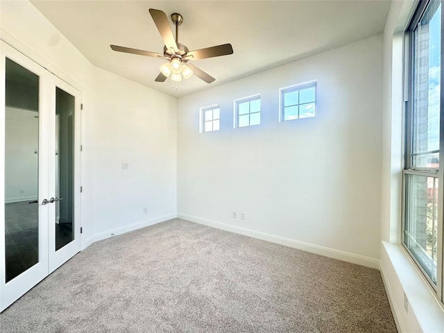 carpeted spare room featuring ceiling fan, french doors, and baseboards