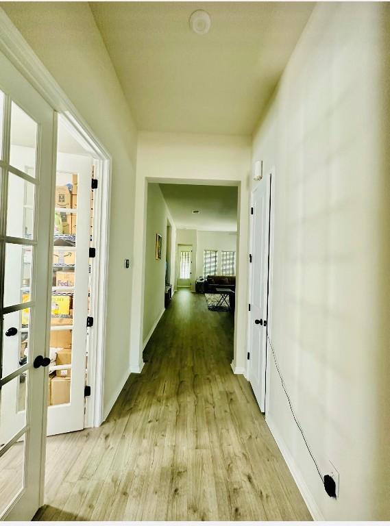 hall with french doors and light hardwood / wood-style flooring