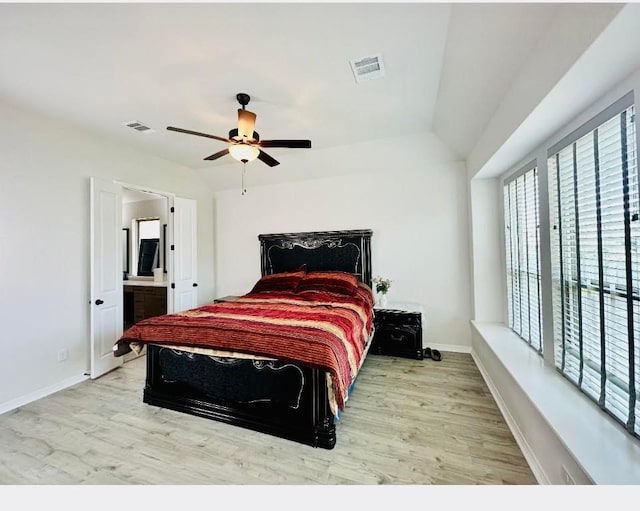 bedroom with ensuite bath, vaulted ceiling, ceiling fan, and light wood-type flooring