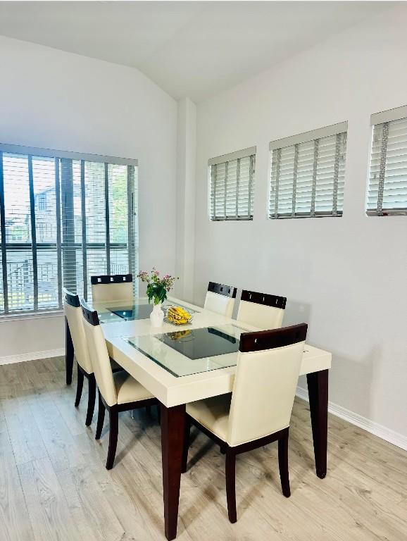 dining space with lofted ceiling and light hardwood / wood-style flooring