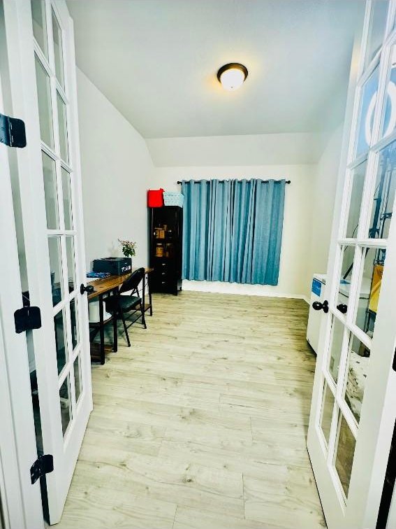 home office with light wood-type flooring and french doors