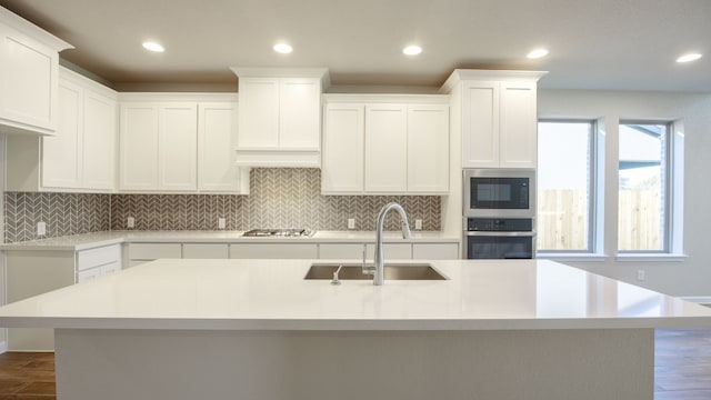 kitchen with appliances with stainless steel finishes, sink, a center island with sink, and white cabinets