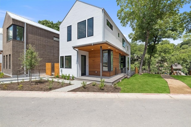 contemporary home with covered porch and a front yard