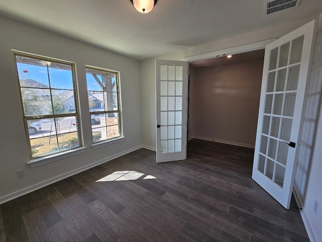 empty room with a mountain view, french doors, dark wood-type flooring, and a textured ceiling