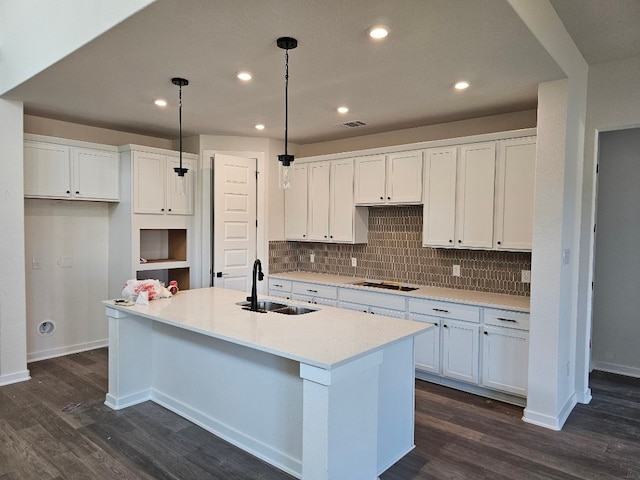 kitchen with white cabinets, a kitchen island with sink, and sink