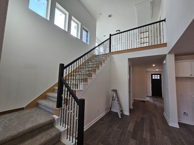 stairs with a high ceiling, a wealth of natural light, and hardwood / wood-style floors