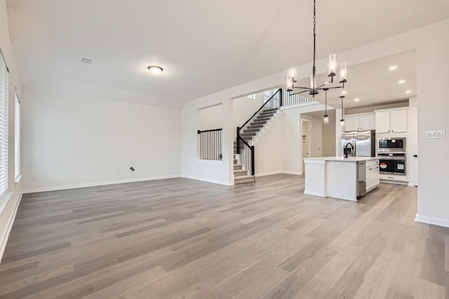 unfurnished living room with light hardwood / wood-style floors and an inviting chandelier