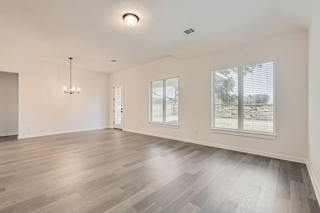 unfurnished living room with a chandelier and wood-type flooring