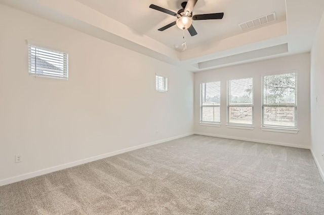 unfurnished room with ceiling fan, a tray ceiling, and carpet flooring