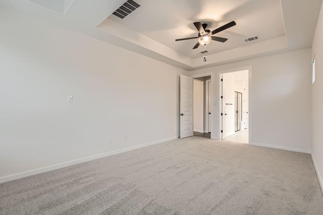 carpeted spare room featuring a raised ceiling and ceiling fan