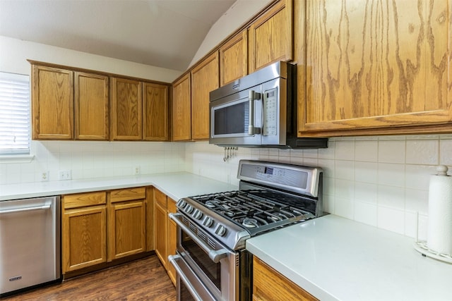 kitchen featuring vaulted ceiling, dark hardwood / wood-style floors, stainless steel appliances, and backsplash