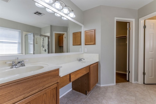 bathroom featuring a shower with door, double vanity, and tile patterned floors