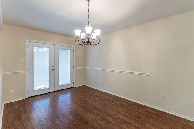 spare room featuring an inviting chandelier, dark wood-type flooring, and french doors