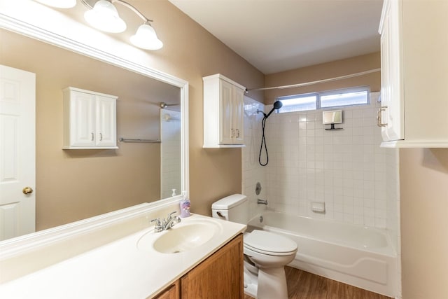 full bathroom featuring vanity, tiled shower / bath, wood-type flooring, and toilet