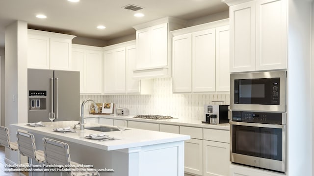 kitchen with a center island with sink, white cabinetry, sink, and appliances with stainless steel finishes