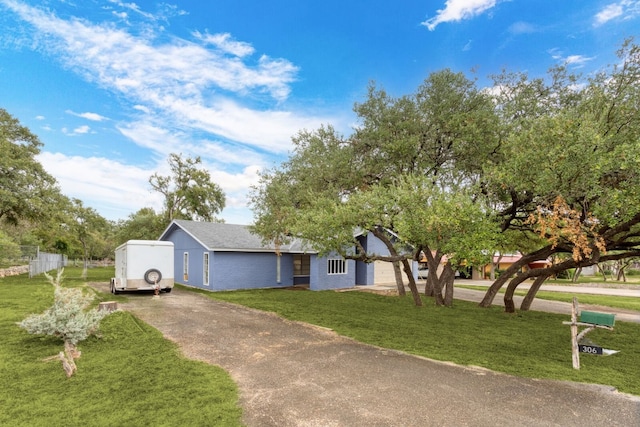 view of front of property with concrete driveway, a front yard, and fence