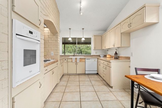 kitchen featuring lofted ceiling, white appliances, light tile patterned flooring, and hanging light fixtures