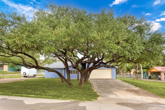 view of front of house with concrete driveway, a front yard, and a garage