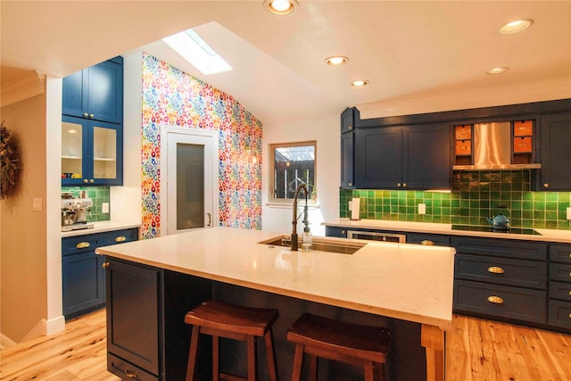 kitchen with black electric stovetop, vaulted ceiling with skylight, sink, a breakfast bar, and an island with sink