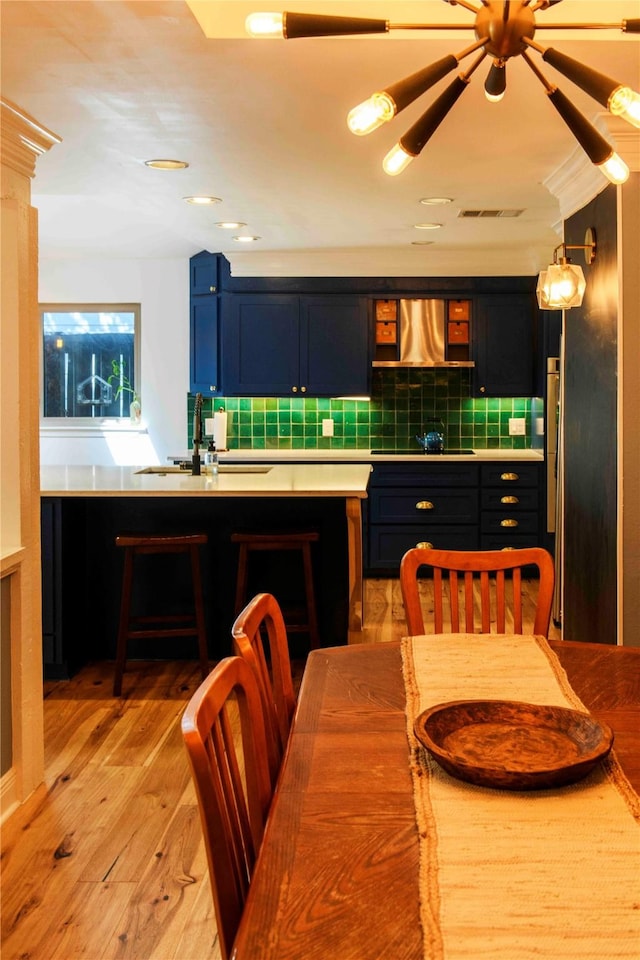 kitchen with ornate columns, sink, wall chimney exhaust hood, light wood-type flooring, and black electric stovetop