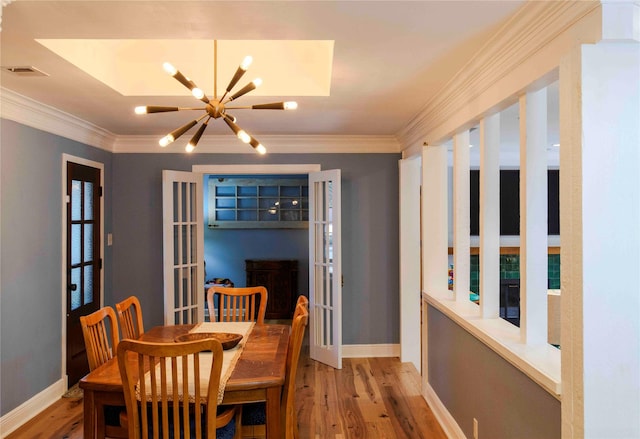 dining space with french doors, light hardwood / wood-style flooring, crown molding, and a chandelier