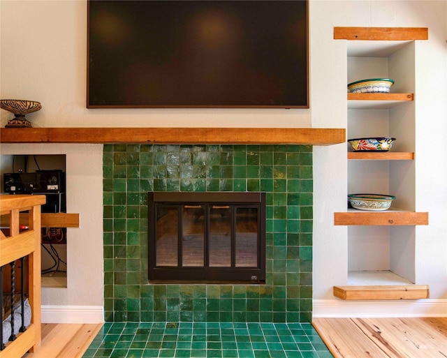 interior details featuring built in features, hardwood / wood-style floors, and a tile fireplace