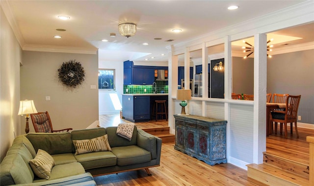 living room with sink, crown molding, and light wood-type flooring