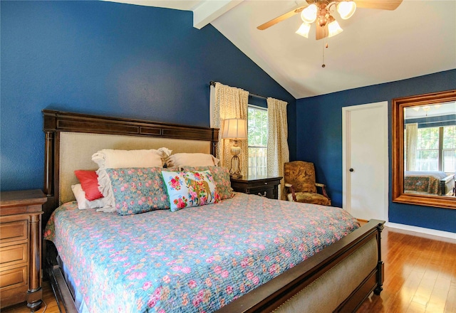 bedroom with ceiling fan, vaulted ceiling with beams, and hardwood / wood-style flooring