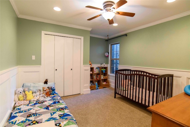 carpeted bedroom featuring ceiling fan, a closet, and crown molding